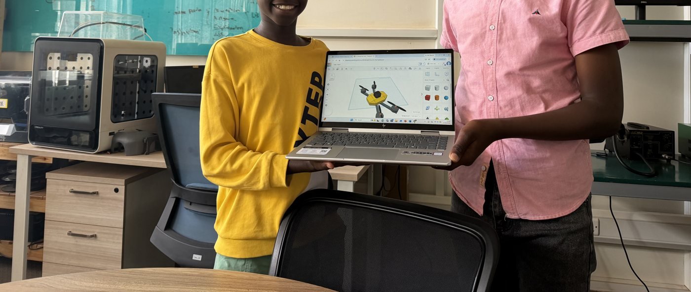 Two AeRoCAD learners proudly holding a laptop showing their CAD design