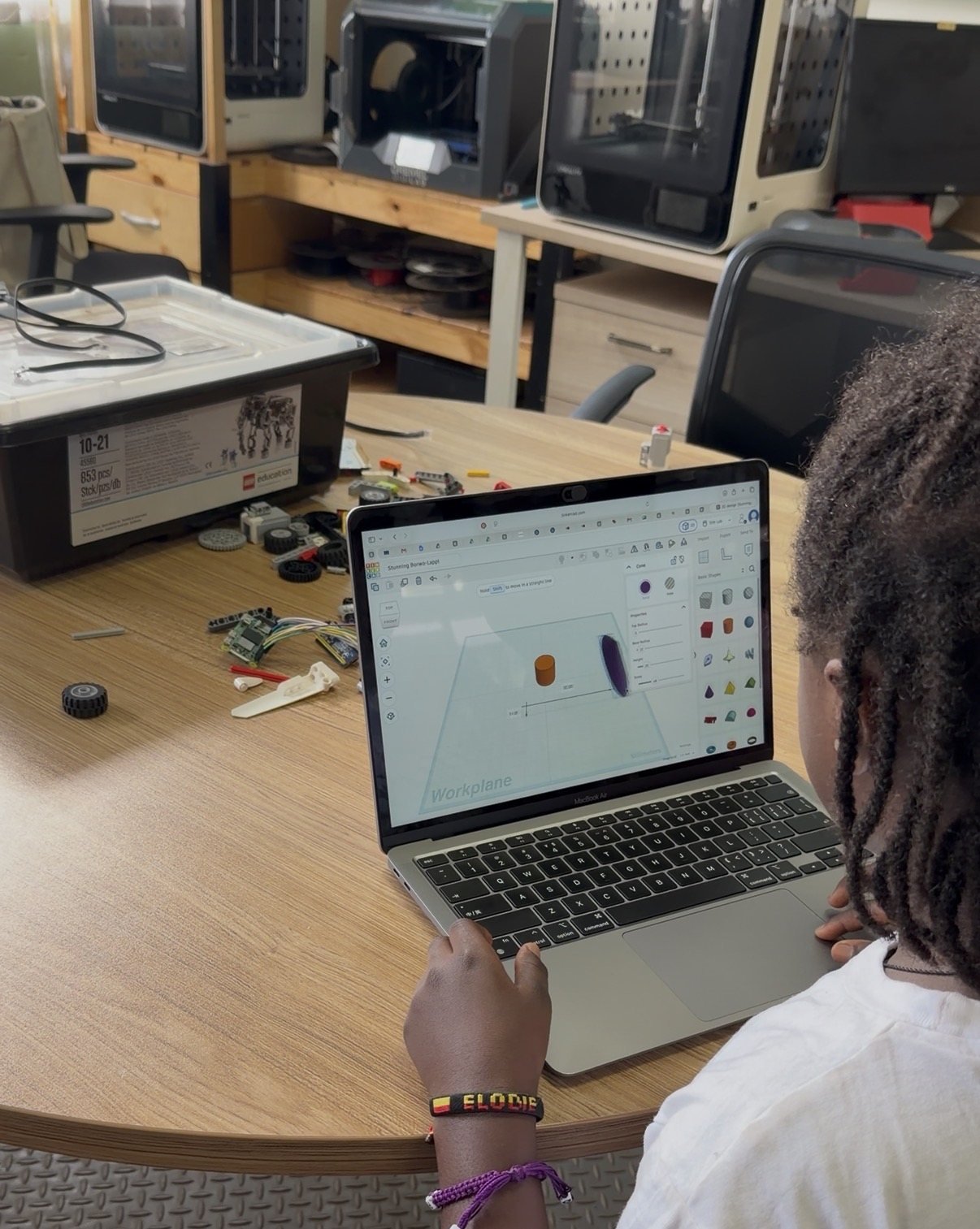 A learner modelling a 3D part in CAD with a robotics kit on the table